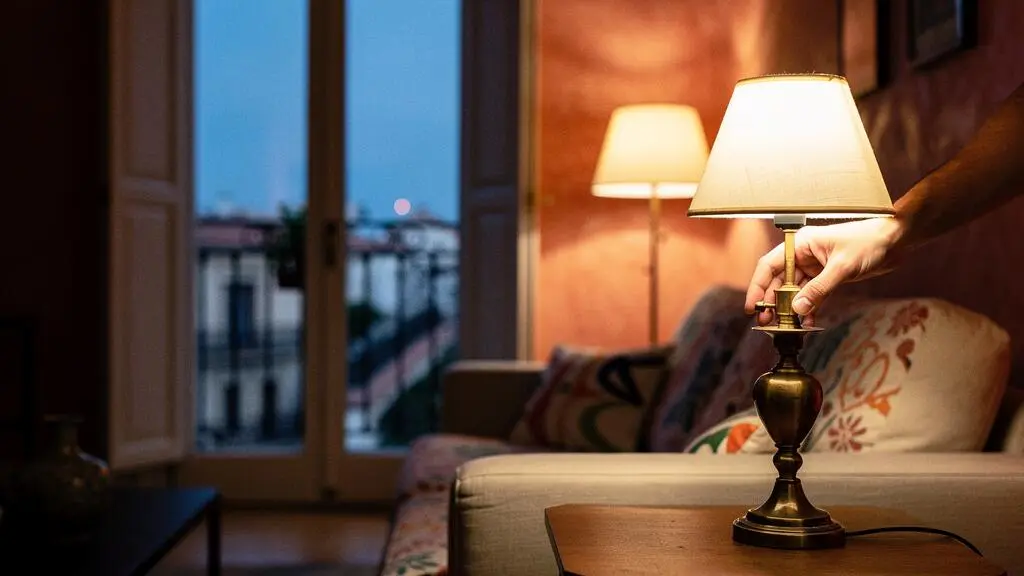 Salón de un piso español al atardecer con distintas fuentes de luz cálida creando ambiente acogedor