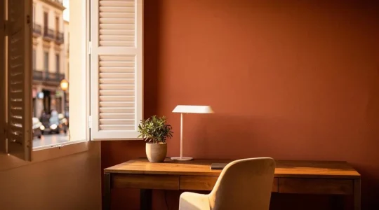 Espacio de home-office luminoso con luz natural cálida entrando por una ventana en un piso español, creando un ambiente de trabajo confortable para la vista