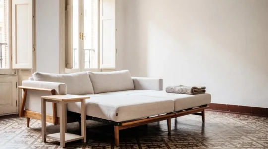 Salón luminoso de un piso español con un sofá modular transformándose en cama, simbolizando un mueble multifuncional real