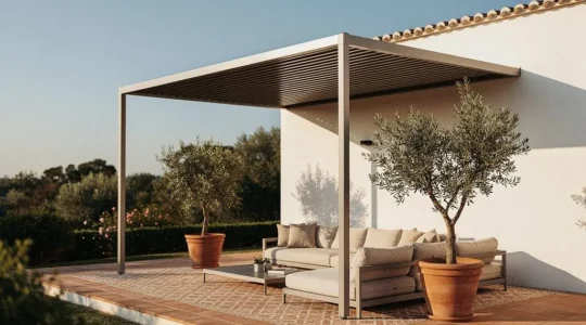 Pérgola moderna de aluminio adosada a la fachada de una vivienda mediterránea española, integrada con elegancia junto a un salón exterior