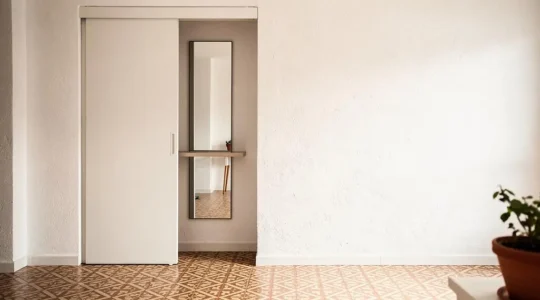 Puerta corredera empotrada integrada en la pared de un salón luminoso de estilo español, mostrando el espacio ganado junto al marco
