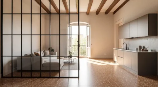 Mampara de vidrio tipo taller separando el salon y la cocina de un piso luminoso en Espana, dejando pasar la luz natural